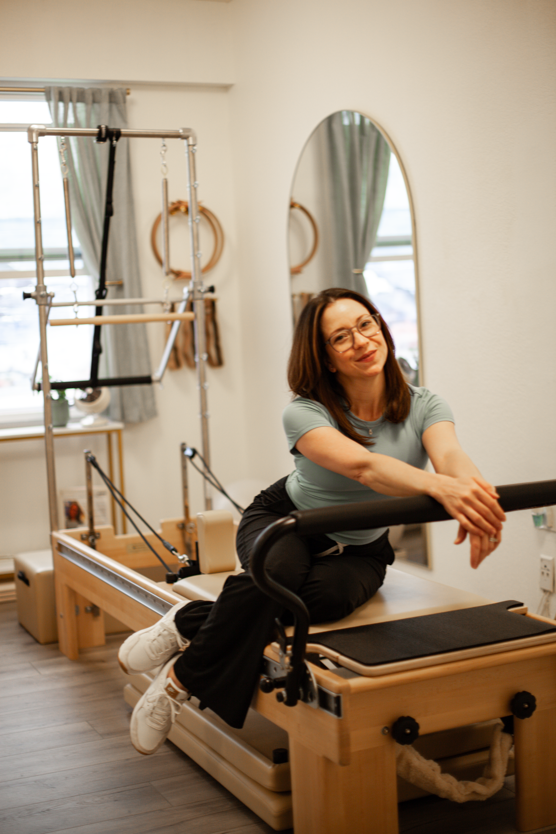 Woman sitting on a Pilates reformer in a private studio space