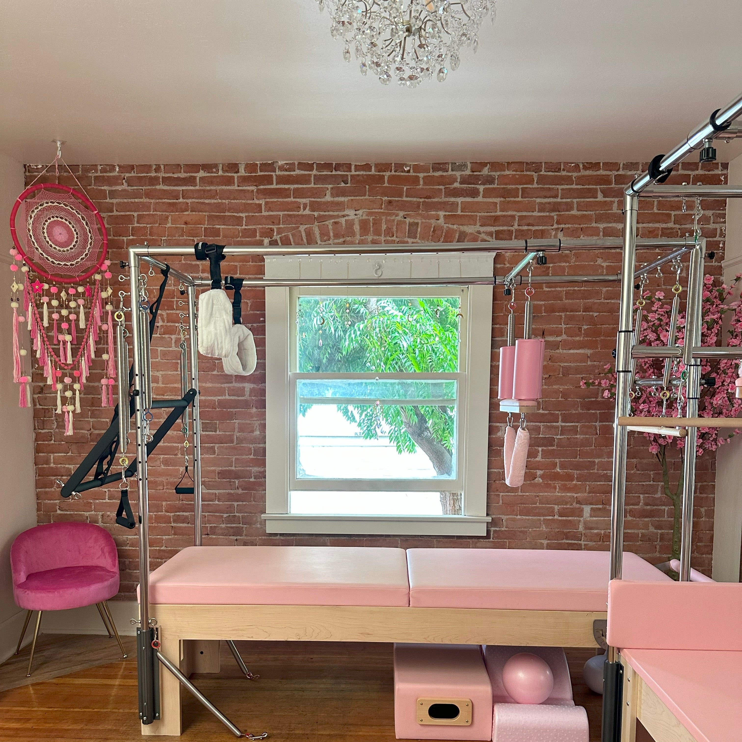 Pink exercise equipment in a room with brick walls and a window.