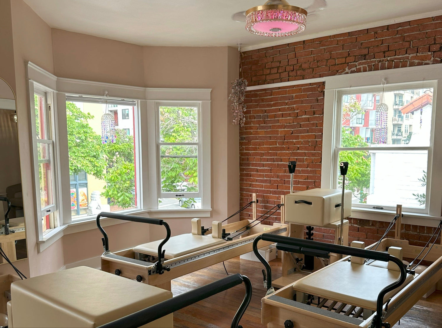Pilates reformers in a room with large windows and brick wall.